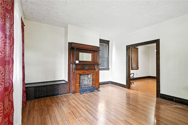 419 8th Ave, Patterson Heights, PA 15010 - unfurnished living room with wood finished floors, a brick fireplace, and a textured ceiling