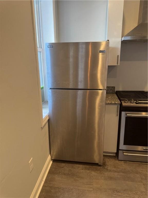 2411 Sarah St, South Side, PA 15203 - kitchen with appliances with stainless steel finishes, wall chimney range hood, white cabinetry, and wood finished floors