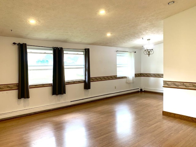 840 Lansberry Ct, Somerset Boro, PA 15501 - unfurnished room featuring a textured ceiling, a chandelier, healthy amount of natural light, wood finished floors, and a baseboard heating unit