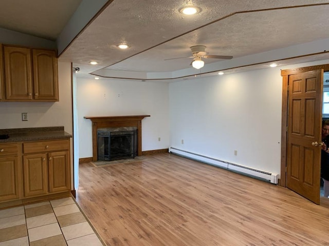 840 Lansberry Ct, Somerset Boro, PA 15501 - unfurnished living room with baseboard heating, a ceiling fan, light wood finished floors, a fireplace with flush hearth, and a textured ceiling