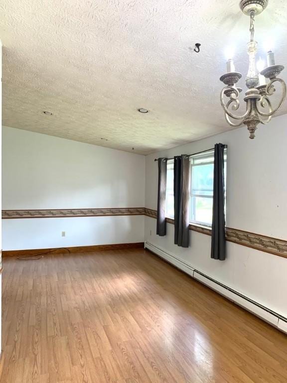 840 Lansberry Ct, Somerset Boro, PA 15501 - empty room featuring a textured ceiling, a chandelier, baseboard heating, and light wood-style flooring