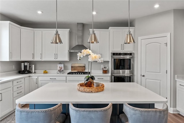 107 Valley View Dr, Brighton Twp, PA 15009 - kitchen with wall chimney range hood, stainless steel double oven, a kitchen breakfast bar, a kitchen island, and light countertops