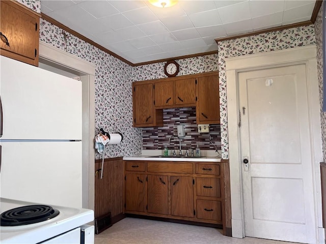 1613 E Washington St, New Castle, PA 16101 - kitchen featuring freestanding refrigerator, wallpapered walls, brown cabinets, crown molding, and light countertops