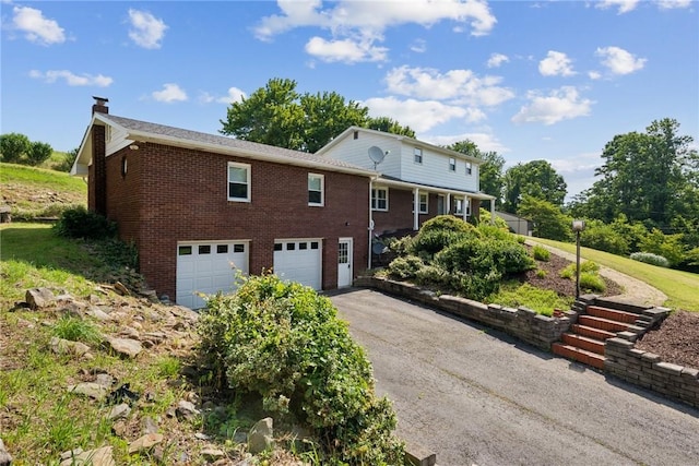 359 Meadow Spring Rd, Unity Twp, PA 15650 - view of property exterior with a garage, asphalt driveway, brick siding, and a chimney