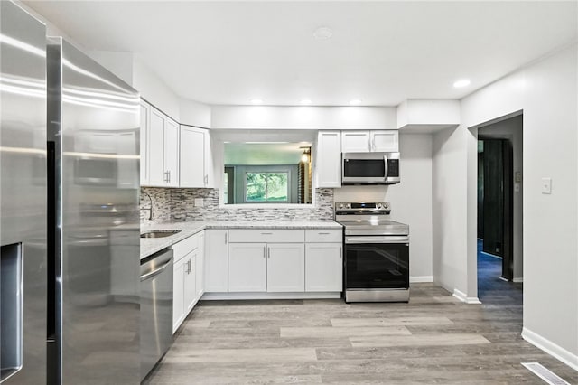 1014 Deerfield Dr, Elizabeth Twp/Boro, PA 15037 - kitchen with stainless steel appliances, light wood-type flooring, white cabinetry, tasteful backsplash, and light stone countertops