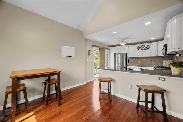 121 Fairway Landings Dr, Cecil, PA 15317 - kitchen featuring a peninsula, dark countertops, backsplash, dark wood finished floors, and a kitchen bar