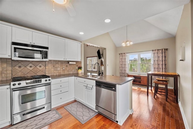 121 Fairway Landings Dr, Cecil, PA 15317 - kitchen with appliances with stainless steel finishes, a peninsula, lofted ceiling, light wood-style flooring, and white cabinetry