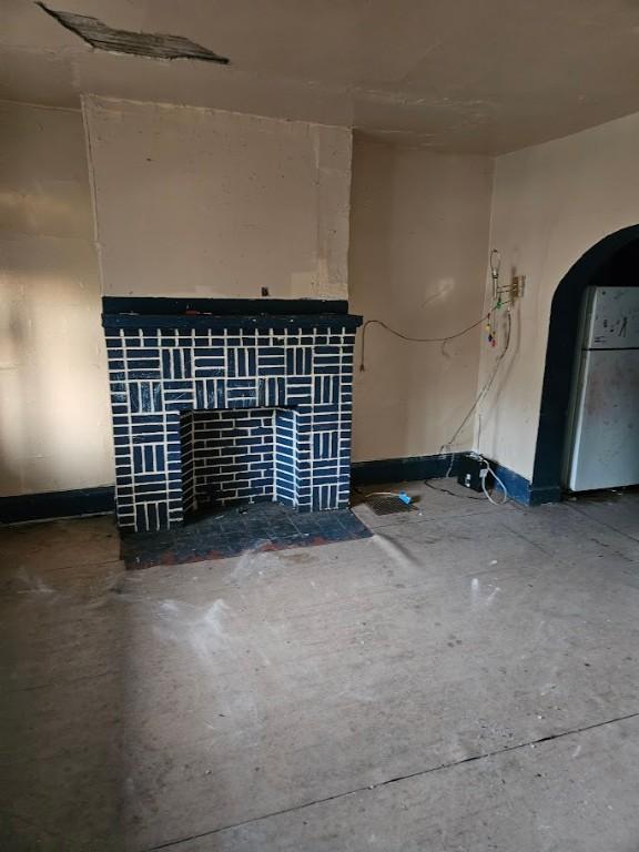 324 Moore Ave, Knoxville, PA 15210 - unfurnished living room featuring concrete flooring, a fireplace, and arched walkways