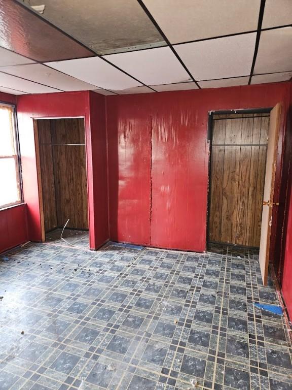 324 Moore Ave, Knoxville, PA 15210 - unfurnished bedroom featuring a drop ceiling, wooden walls, and tile patterned floors