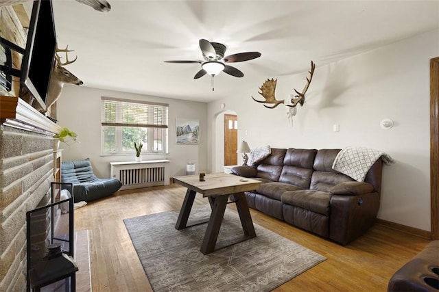 1045 Beverly Ave, Ambridge, PA 15003 - living area with arched walkways, radiator, wood finished floors, ceiling fan, and a fireplace