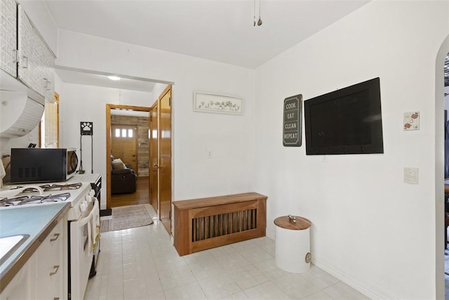 1045 Beverly Ave, Ambridge, PA 15003 - kitchen featuring white range with gas stovetop, white cabinetry, arched walkways, and light countertops