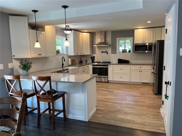 4689 Greenwood Dr, Hampton, PA 15101 - kitchen featuring wall chimney exhaust hood, stainless steel appliances, a peninsula, light stone counters, and white cabinetry