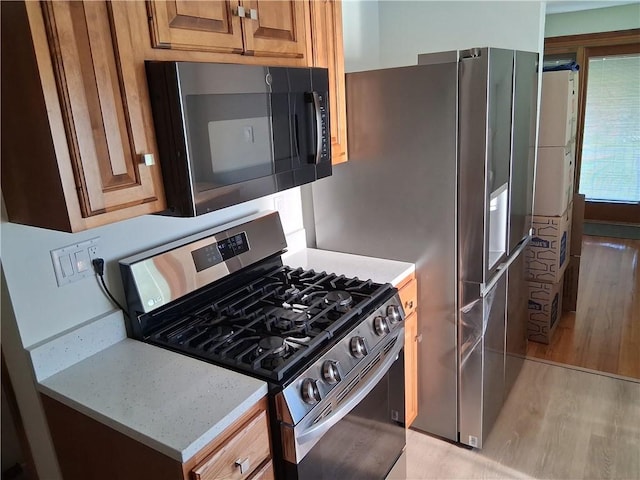 4977 Meadow Park Dr, Whitehall, PA 15236 - kitchen with gas stove, light wood-style flooring, brown cabinetry, and light stone counters
