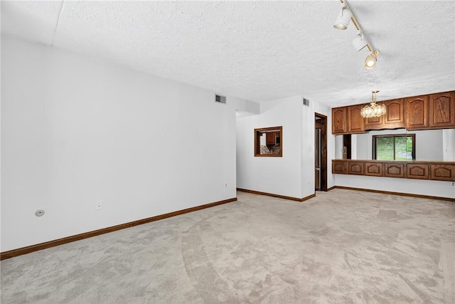 2011 Thornberry Dr, Ross Twp, PA 15237 - unfurnished living room featuring a chandelier, light colored carpet, a textured ceiling, and track lighting