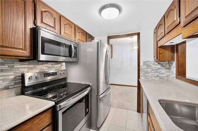 2011 Thornberry Dr, Ross Twp, PA 15237 - kitchen featuring stainless steel appliances, light tile patterned floors, brown cabinetry, and decorative backsplash