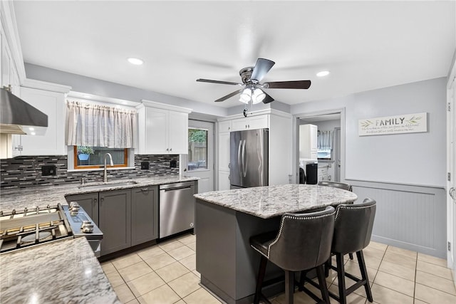 1615 Wicklines Ln, Troy Hill, PA 15212 - kitchen featuring appliances with stainless steel finishes, ceiling fan, light tile patterned flooring, wall chimney exhaust hood, and wainscoting