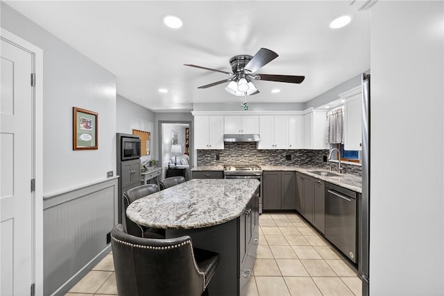 1615 Wicklines Ln, Troy Hill, PA 15212 - kitchen featuring appliances with stainless steel finishes, under cabinet range hood, a center island, light tile patterned floors, and ceiling fan