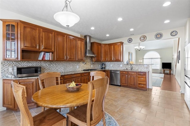 304 Horizon Dr, Monroeville, PA 15146 - kitchen with appliances with stainless steel finishes, wall chimney range hood, a peninsula, decorative backsplash, and hanging light fixtures