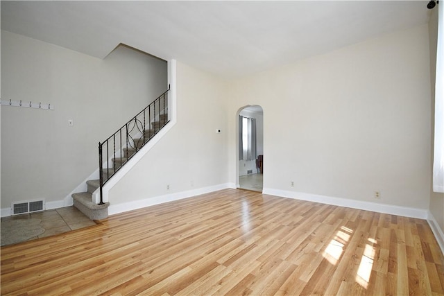 404 Emerson, Munhall, PA 15120 - spare room featuring arched walkways, light wood-style flooring, and stairs