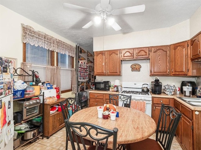 109 Ella St, Mckees Rocks, PA 15136 - kitchen with white gas stove, a ceiling fan, light countertops, brown cabinetry, and a textured ceiling