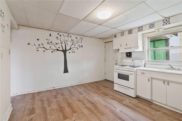 302 38th St, Lawrenceville, PA 15201 - kitchen with gas range gas stove, light wood-style floors, under cabinet range hood, white cabinets, and a paneled ceiling