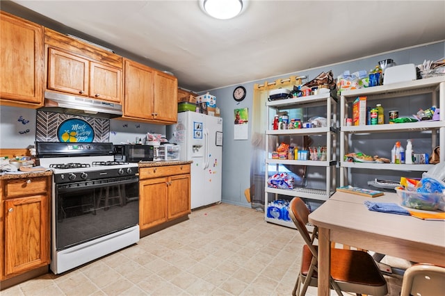 1807 Packer, Mckeesport, PA 15132 - kitchen featuring gas range oven, under cabinet range hood, white refrigerator with ice dispenser, light floors, and brown cabinets