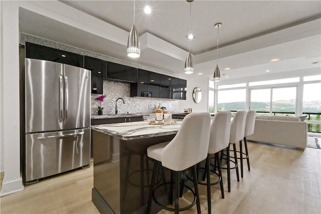 2613 Stella St, South Side, PA 15203 - kitchen with freestanding refrigerator, dark cabinets, decorative backsplash, light wood-type flooring, and a kitchen island