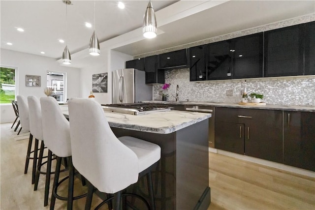 2613 Stella St, South Side, PA 15203 - kitchen with appliances with stainless steel finishes, a kitchen island, backsplash, light wood-style floors, and recessed lighting