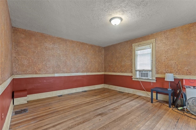 1345 N Tower Rd, Perry Twp, PA 16123 - empty room featuring hardwood / wood-style floors, a textured ceiling, cooling unit, and wallpapered walls