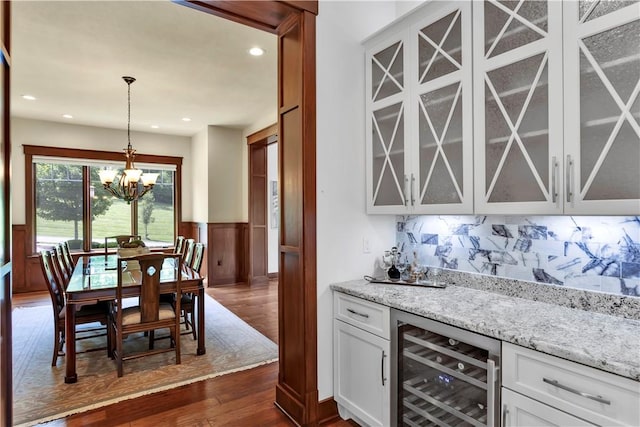 106 Orchard Dr, Pine Twp, PA 15044 - indoor dry bar with beverage cooler, dark wood-style floors, a chandelier, wainscoting, and decorative light fixtures