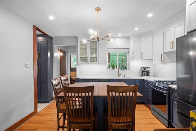 5671 Beacon St, Squirrel Hill, PA 15217 - kitchen featuring stainless steel appliances, tasteful backsplash, a center island, white cabinets, and a chandelier
