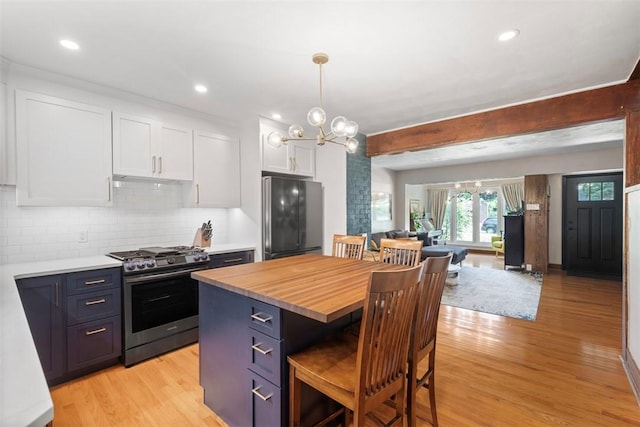 5671 Beacon St, Squirrel Hill, PA 15217 - kitchen featuring stainless steel range with gas stovetop, black refrigerator, white cabinetry, light wood-style floors, and a breakfast bar area