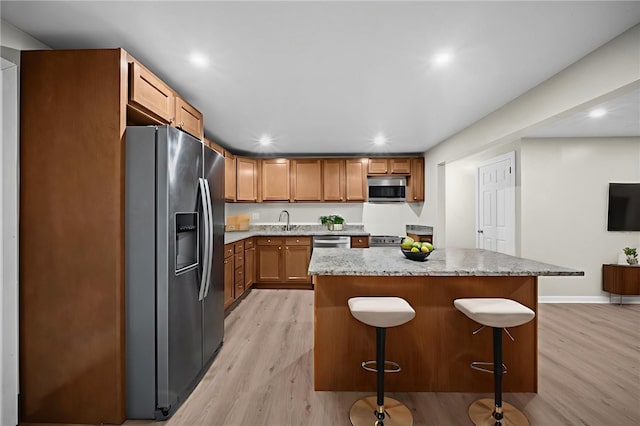 260 Stotler Rd, Penn Hills, PA 15235 - kitchen featuring stainless steel appliances, light wood finished floors, a breakfast bar, light stone counters, and recessed lighting