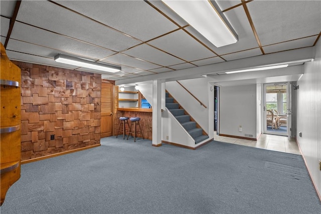 719 12th St, Pitcairn, PA 15140 - basement featuring wooden walls, carpet flooring, stairway, and a bar