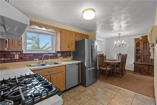719 12th St, Pitcairn, PA 15140 - kitchen featuring appliances with stainless steel finishes, ventilation hood, light countertops, light colored carpet, and a chandelier