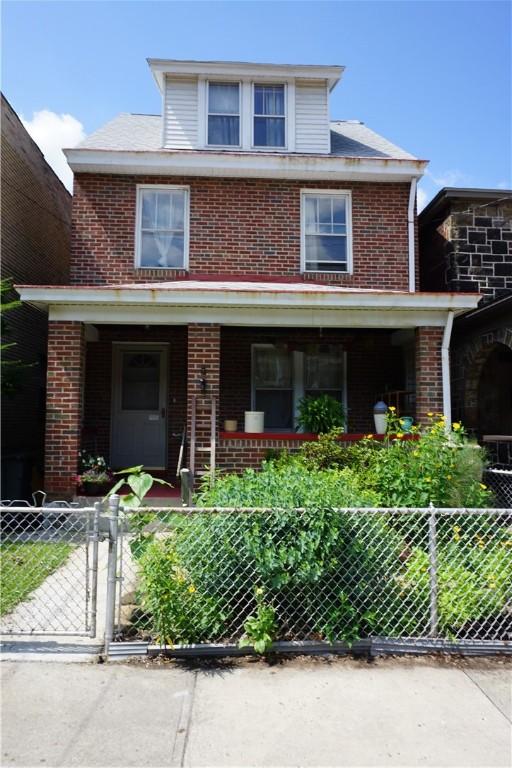 2430 Woodstock Ave, Swissvale, PA 15218 - traditional style home with brick siding, a porch, a fenced front yard, and a gate