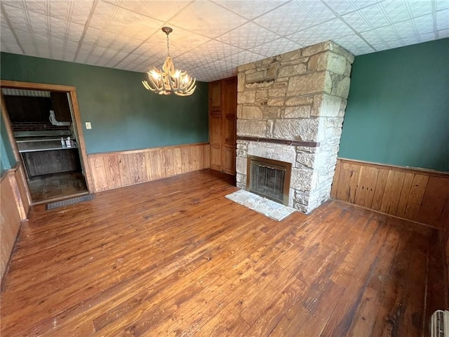 328 Thatcher Rd, Fairfield Twp, PA 15944 - unfurnished living room with a wainscoted wall, a stone fireplace, hardwood / wood-style flooring, a chandelier, and wooden walls