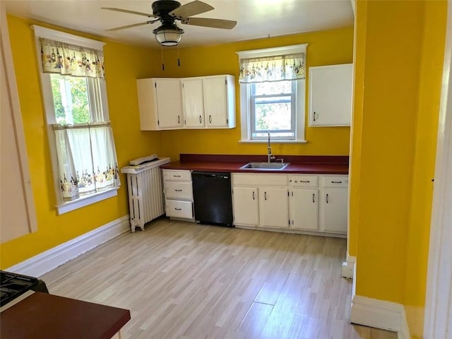 413 N 3rd St, Jeannette, PA 15644 - kitchen featuring black dishwasher, dark countertops, light wood-style floors, white cabinetry, and radiator