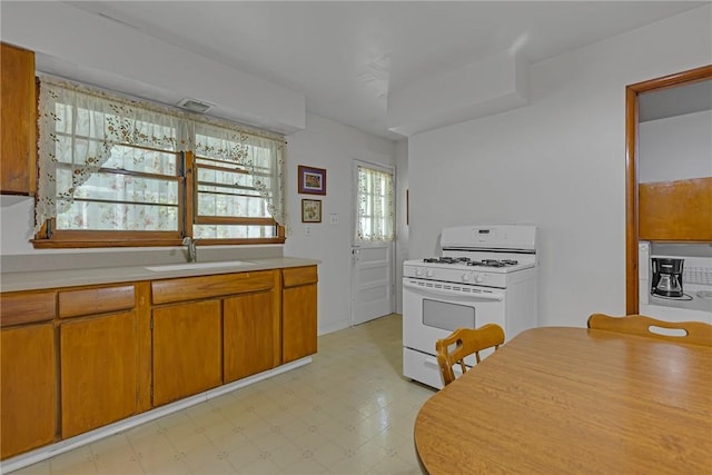 320 Wilson Ave, Beaver, PA 15009 - kitchen featuring white gas range, light countertops, light flooring, and brown cabinetry