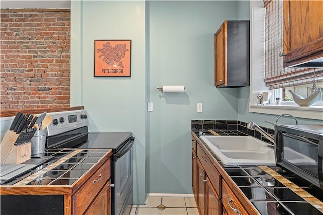 175-177 43rd 1/2 St, Lawrenceville, PA 15201 - kitchen with stainless steel electric range oven, tile counters, brown cabinetry, light tile patterned floors, and brick wall