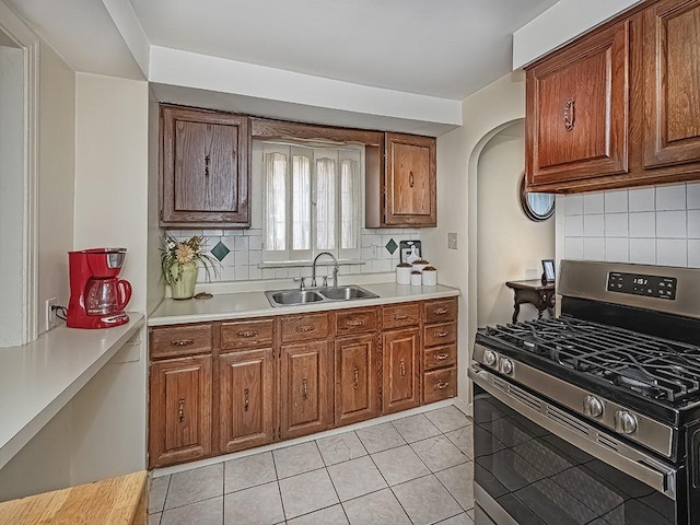 740 Churchill Ave, Penn Hills, PA 15235 - kitchen with stainless steel gas range oven, backsplash, light countertops, brown cabinets, and arched walkways