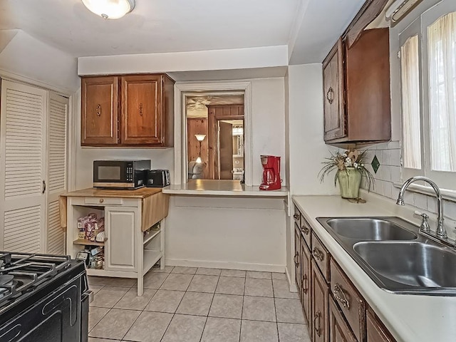 740 Churchill Ave, Penn Hills, PA 15235 - kitchen with light countertops, stainless steel microwave, light tile patterned floors, and brown cabinetry