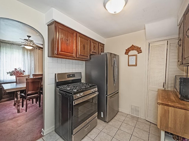 740 Churchill Ave, Penn Hills, PA 15235 - kitchen with appliances with stainless steel finishes, a ceiling fan, light tile patterned floors, decorative backsplash, and brown cabinets
