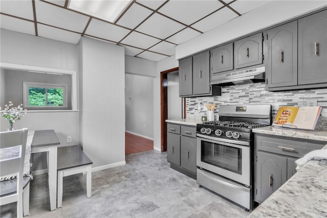 880 Patton St, Monroeville, PA 15146 - kitchen with stainless steel gas stove, under cabinet range hood, gray cabinetry, and decorative backsplash