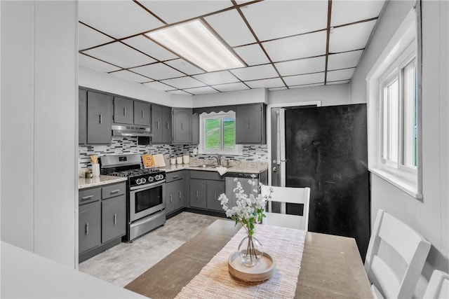 880 Patton St, Monroeville, PA 15146 - kitchen with appliances with stainless steel finishes, under cabinet range hood, gray cabinets, tasteful backsplash, and light countertops