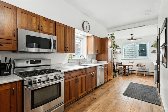 3100 Wainbell Ave, Dormont, PA 15216 - kitchen with appliances with stainless steel finishes, light countertops, a baseboard heating unit, light wood-style flooring, and brown cabinetry