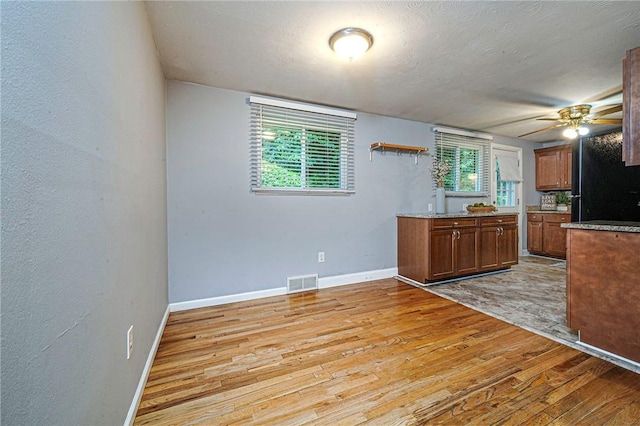 125 Holstein Dr, North Fayette, PA 15071 - kitchen featuring light wood-type flooring, ceiling fan, freestanding refrigerator, brown cabinets, and a textured ceiling