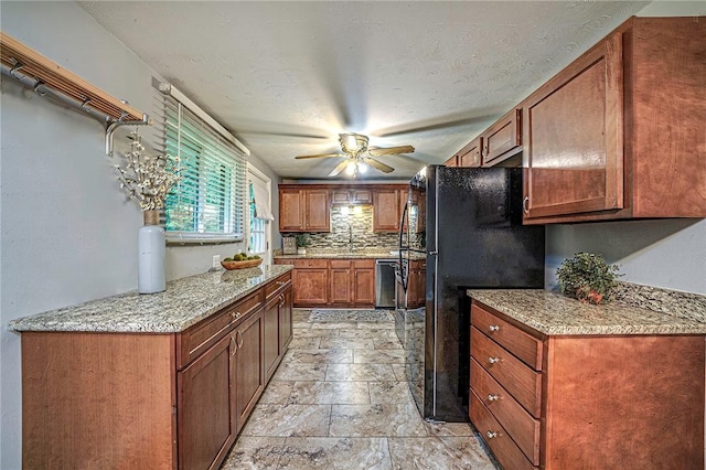 125 Holstein Dr, North Fayette, PA 15071 - kitchen with freestanding refrigerator, ceiling fan, stone tile flooring, tasteful backsplash, and brown cabinets