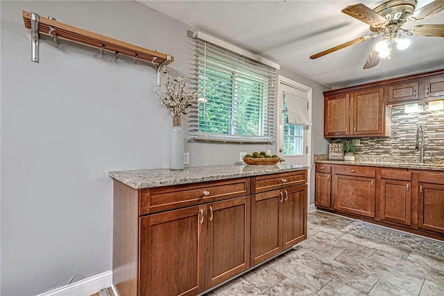 125 Holstein Dr, North Fayette, PA 15071 - kitchen featuring decorative backsplash, ceiling fan, light stone countertops, and brown cabinets