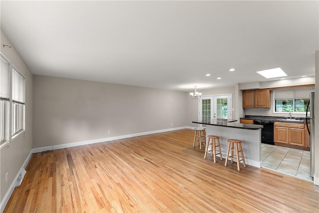 900 Tottenham Dr, Coraopolis, PA 15108 - kitchen with black dishwasher, a kitchen breakfast bar, light wood-style floors, a chandelier, and dark countertops